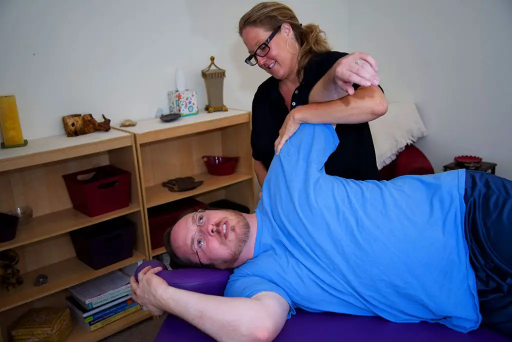 massage therapist stretching shoulder pain