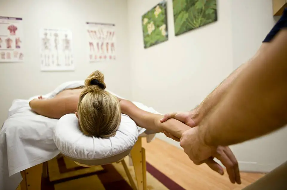 massage therapist stretches client's arm