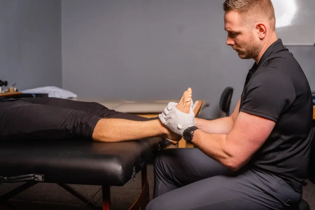 physical therapist examines a patient’s ankle for a sprain or break